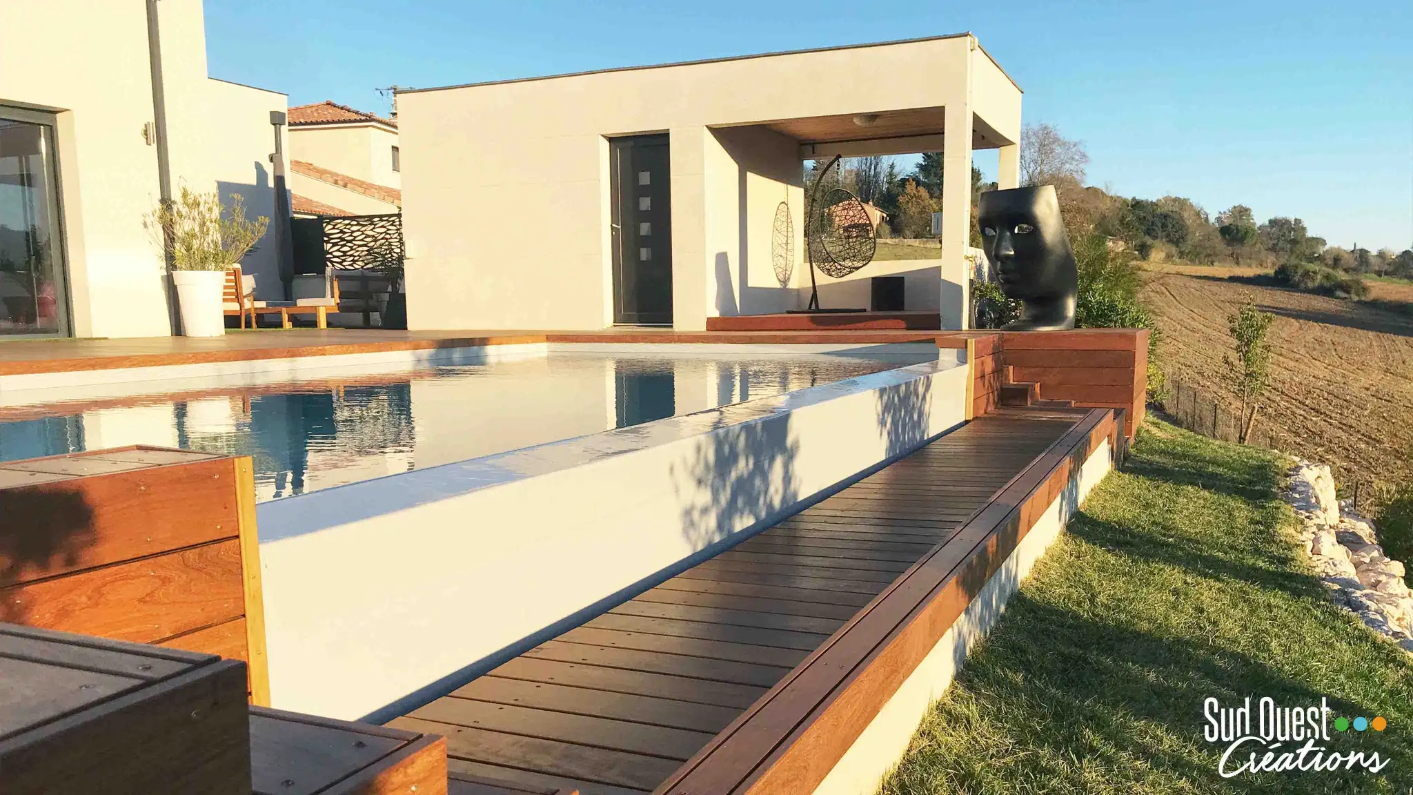 Terrasse en bois IPE devant un pool house contemporain avec muret